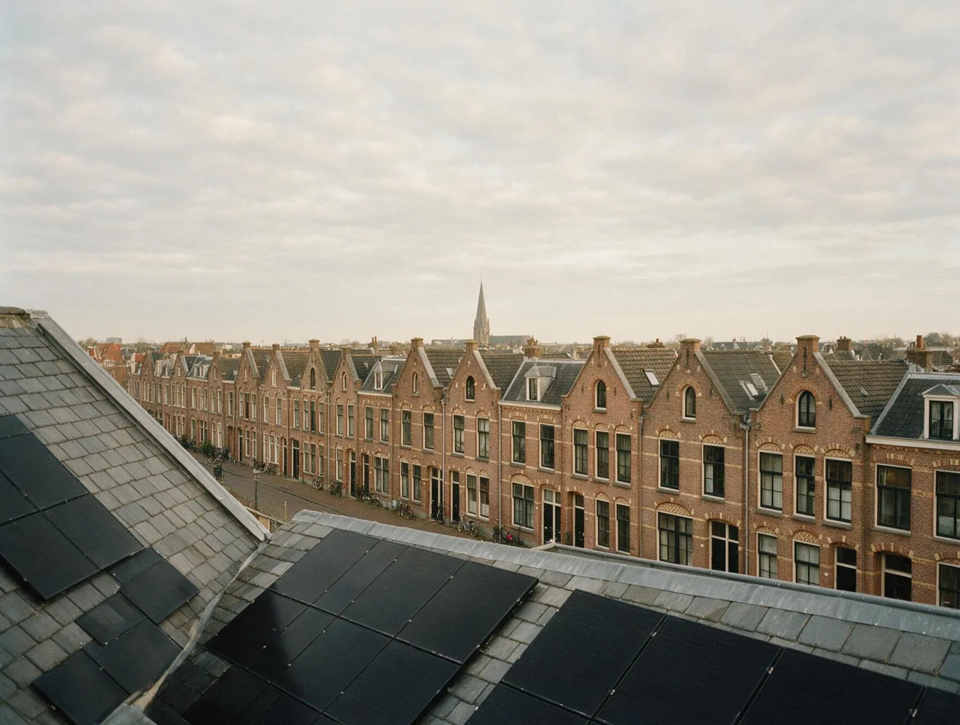 Matte black panels installed flush across a terraced brick roof in Zuid-Holland.